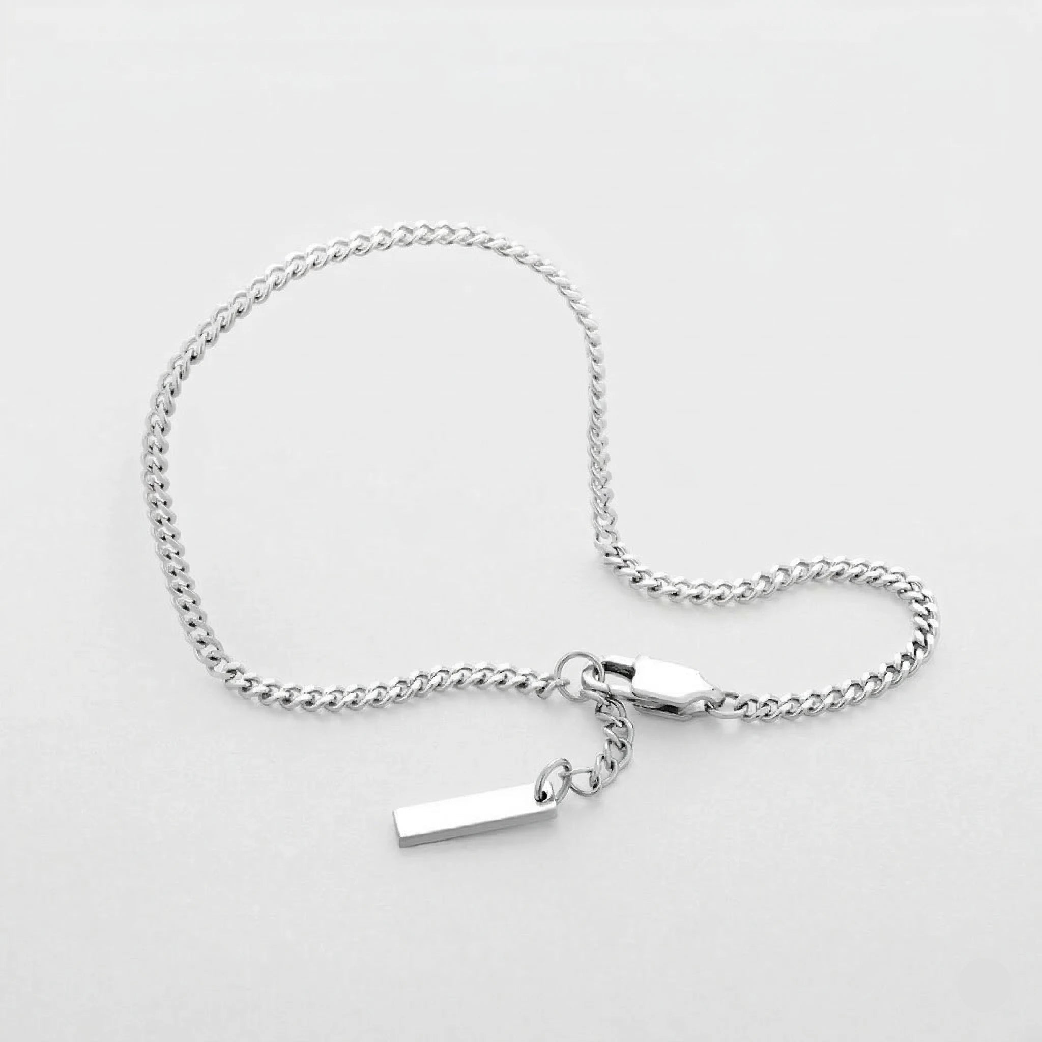 Silver Cuban bracelet with a tag on a light gray background