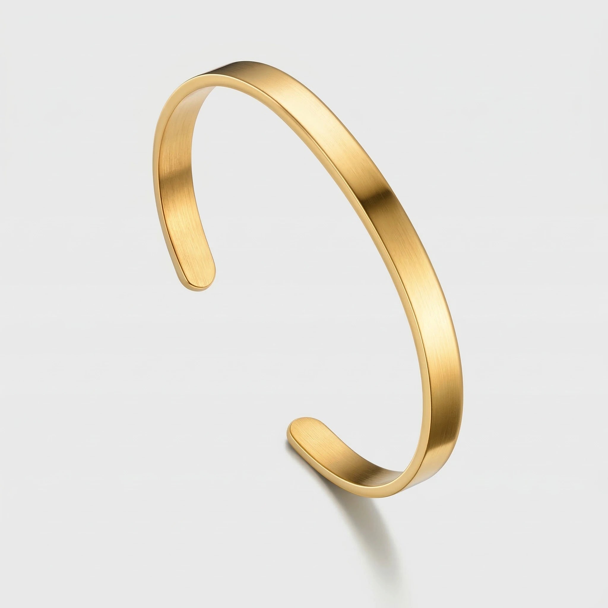 Gold cuff bracelet on a light gray background