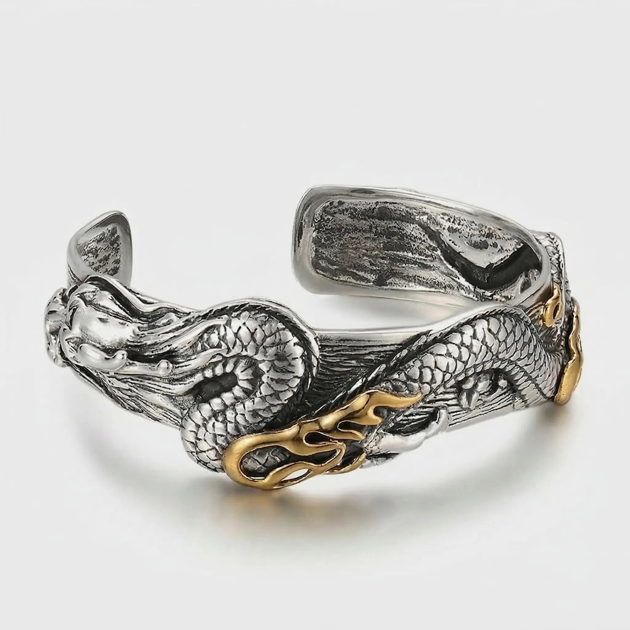 Silver and gold dragon bracelet on a light gray background