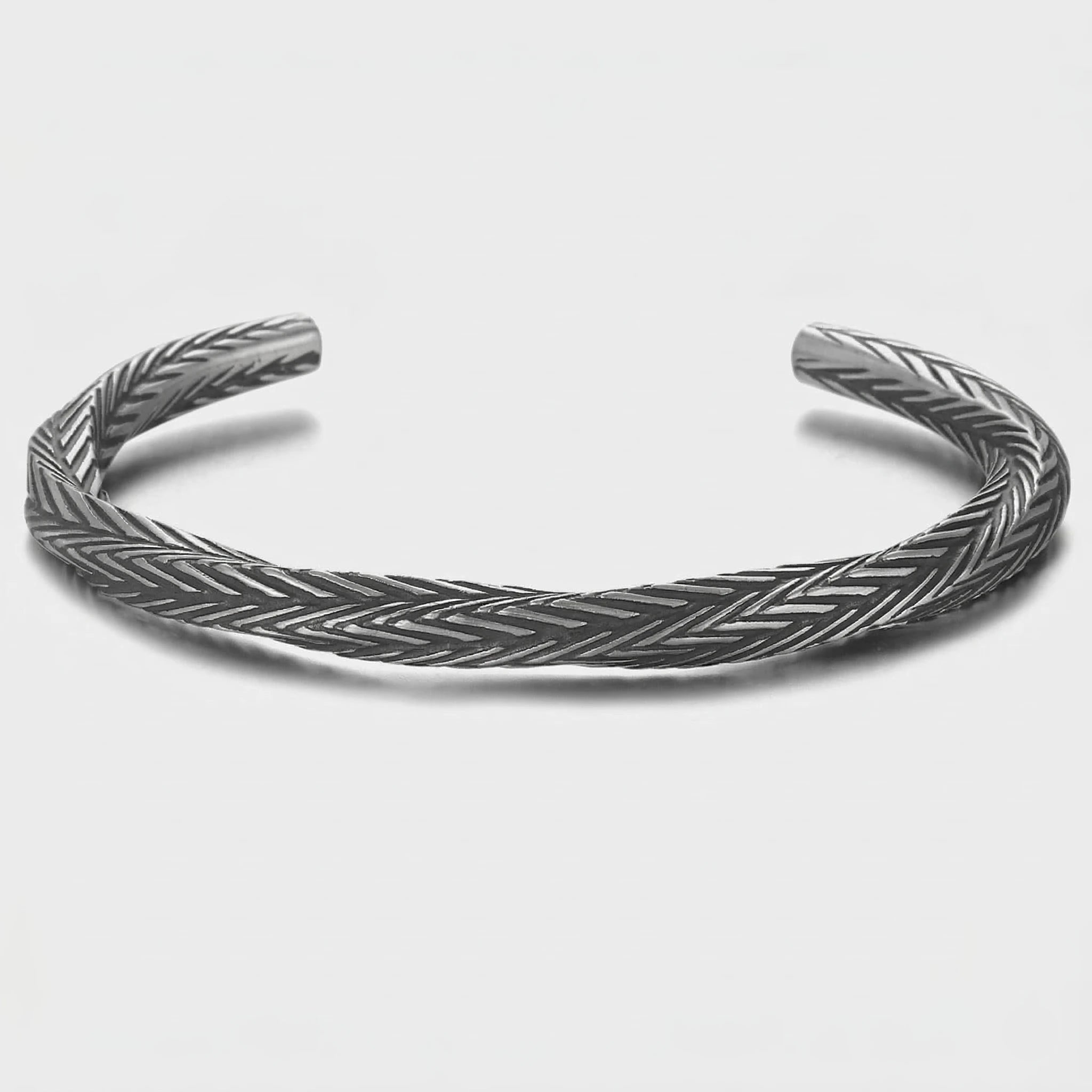 Silver bracelet with a textured pattern on a light gray background