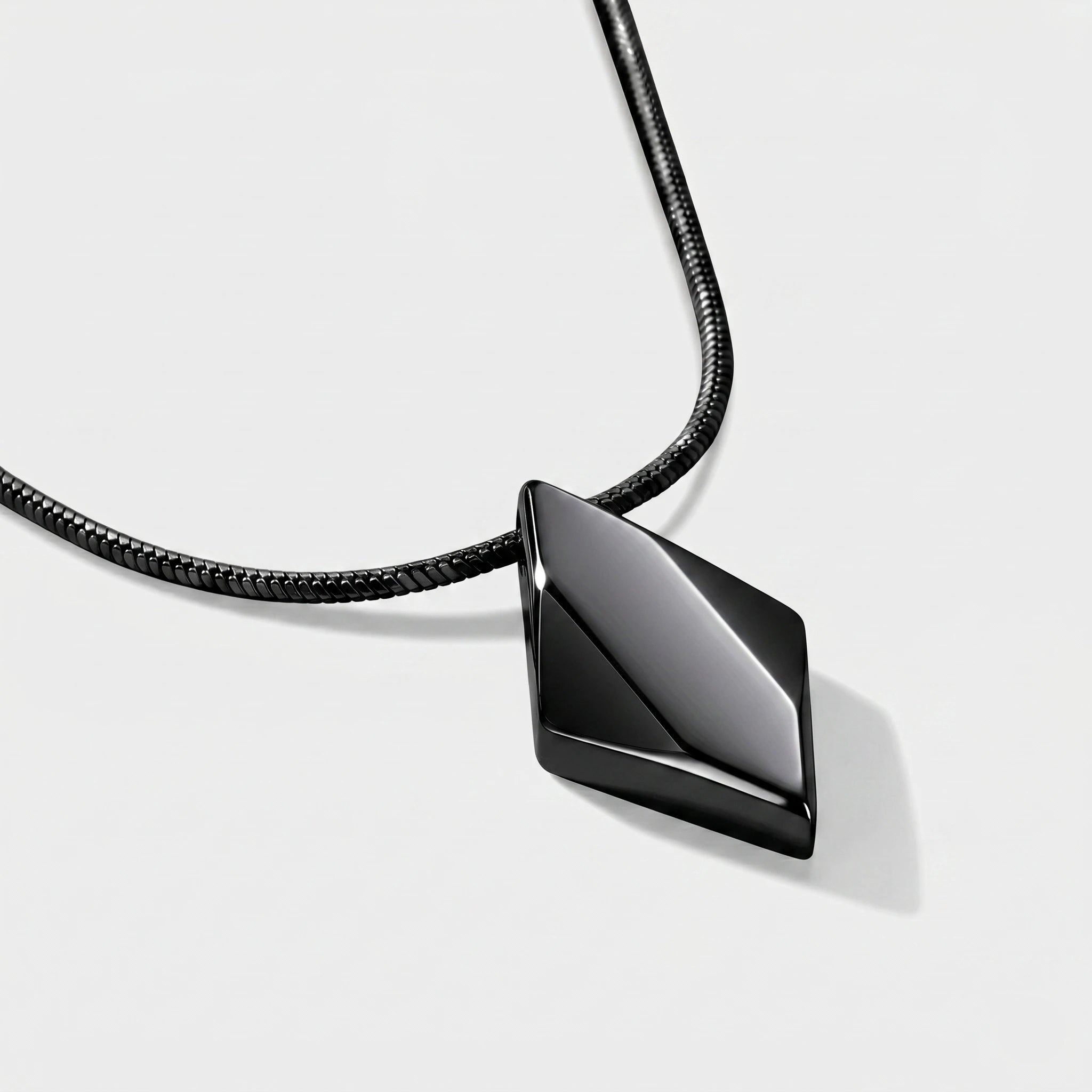 Black geometric pendant on a black cord against a white background