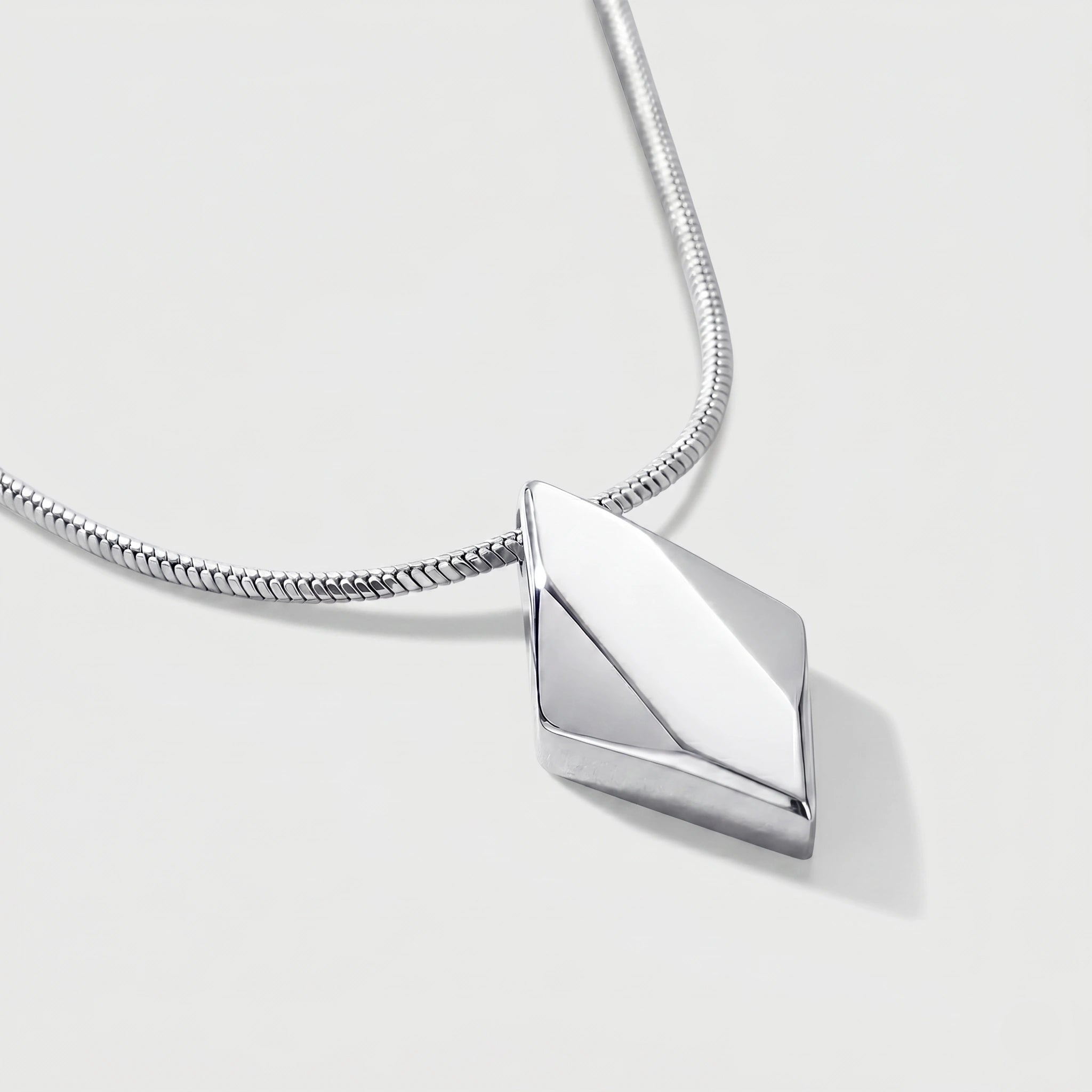 Silver geometric pendant on a chain against a light gray background
