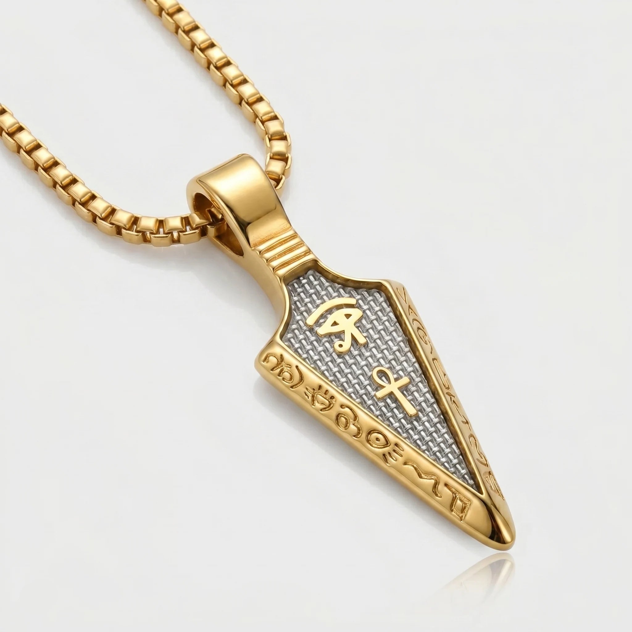 Gold pendant necklace with intricate designs on a light gray background